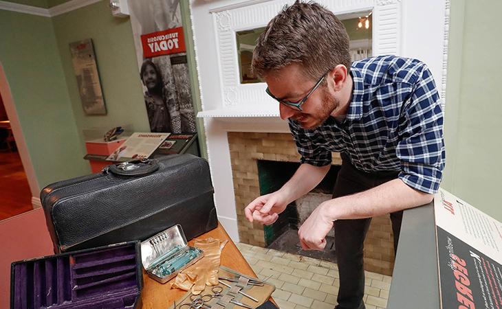 a faculty member shows off items at the Frank Museum